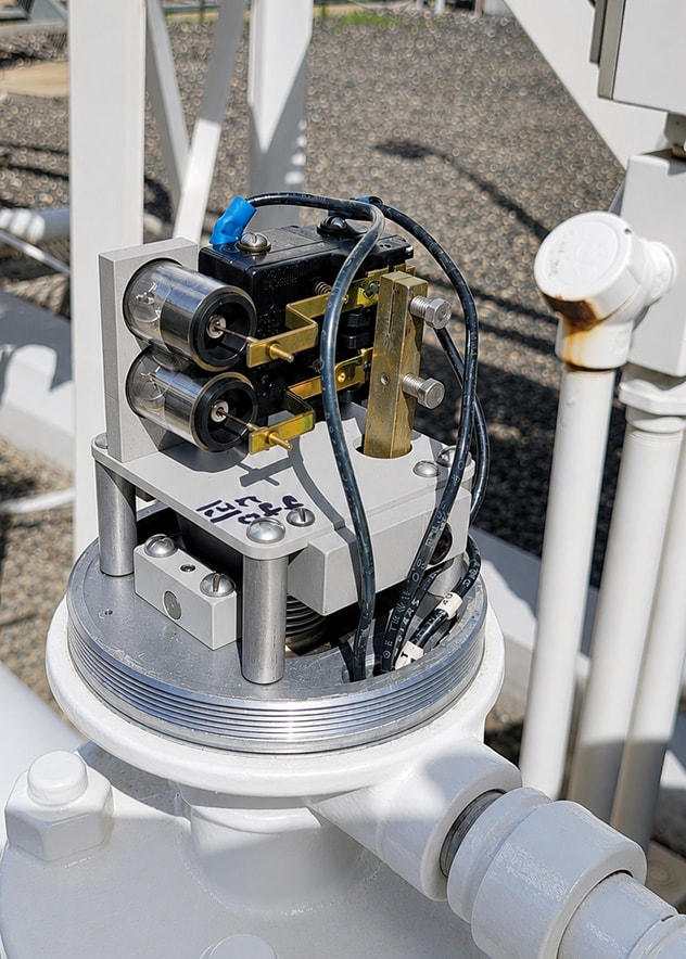 Stacked PEECO Dash Pots installed on a flow switch in an industrial pipeline setting